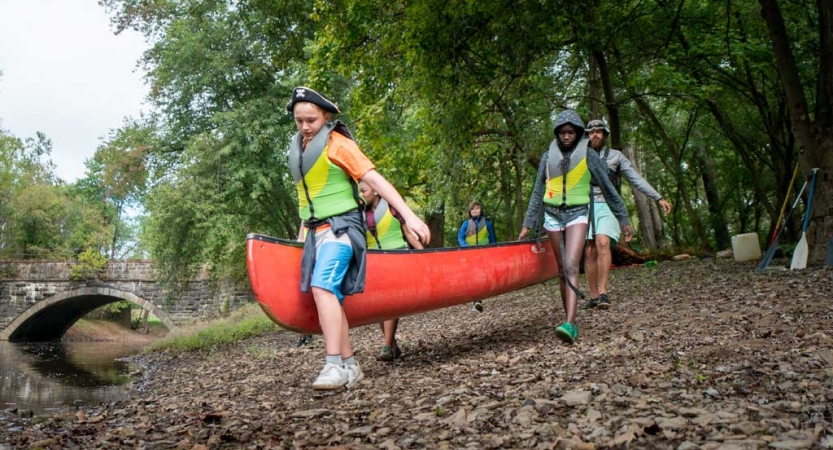 a group of teens carry a canoe to water on an outward bound expedition 